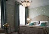 A bedroom with a bed, a nightstand, a lamp, and a vase of flowers.