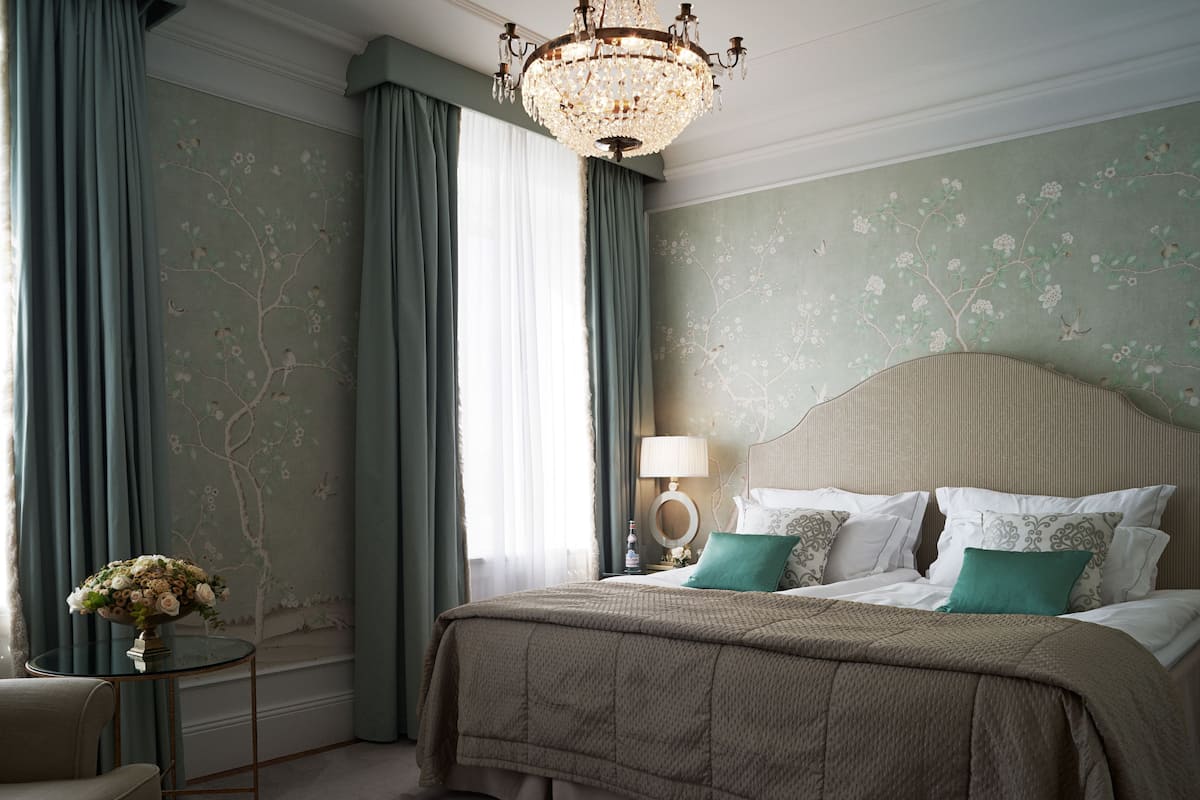 A bedroom with a bed, a nightstand, a lamp, and a vase of flowers.
