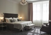 A neatly arranged bedroom with a large bed, bedside lamps, a bench, and a chair.