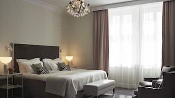 Un dormitorio ordenado con una cama grande, lámparas de noche, un banco y una silla.