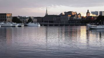 A river with several boats docked, a bridge, and a city skyline with historic buildings.