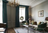 A well-lit room with a chandelier, a sofa, a chair, a coffee table, and a lamp.