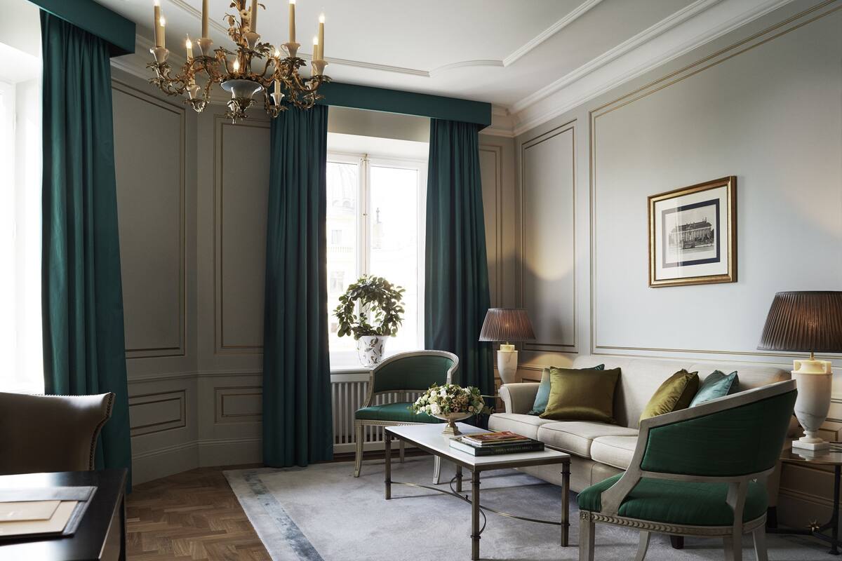 A well-lit room with a chandelier, a sofa, a chair, a coffee table, and a lamp.
