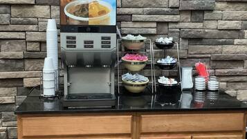 A coffee station with a coffee machine, a sign for iced coffee, and multiple bowls of food.