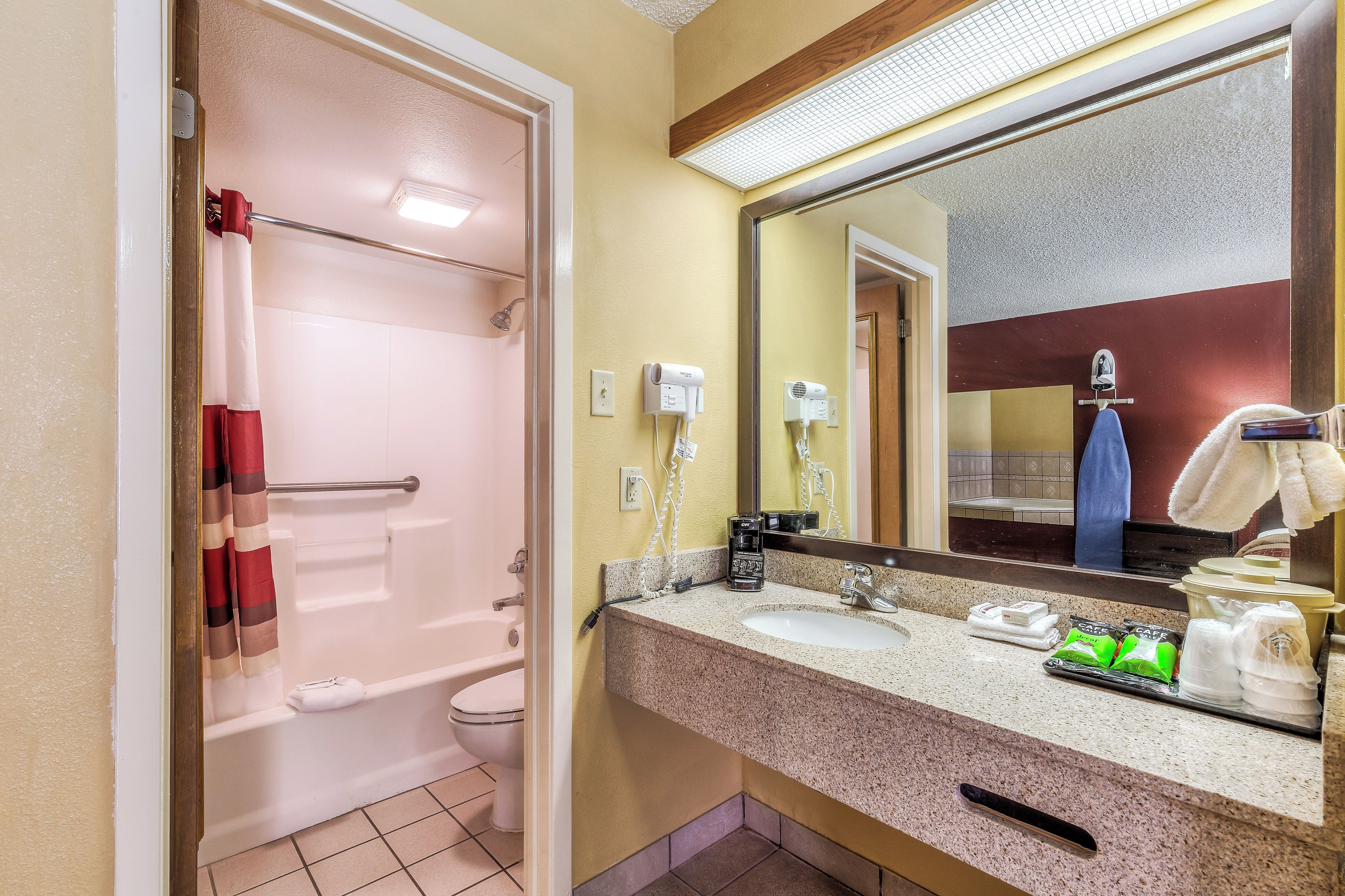 A bathroom with a shower, toilet, sink, and a mirror.