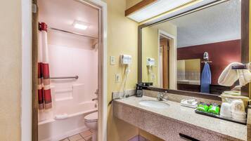 A bathroom with a shower, toilet, sink, and a mirror.