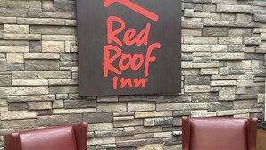 A Red Roof Inn sign on a stone wall with two leather chairs and a small table. - Red Roof Inn Amarillo West (Amarillo)