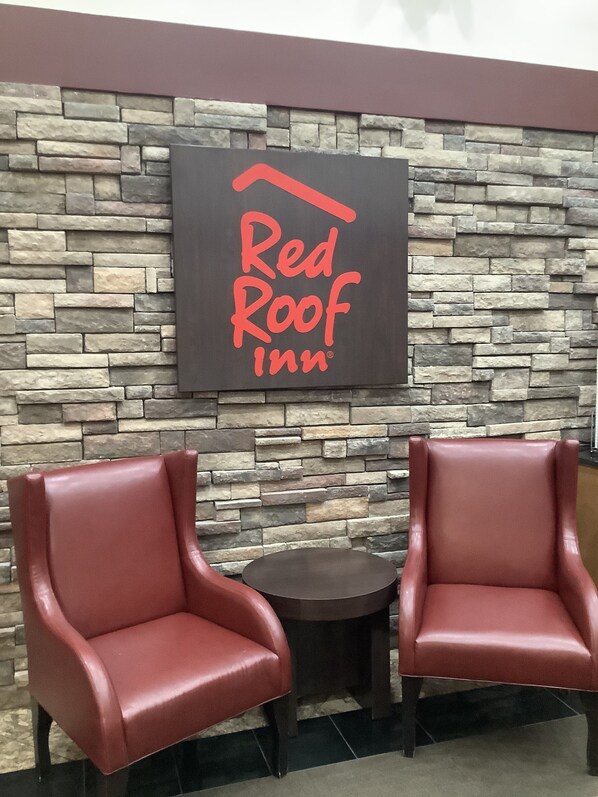 A Red Roof Inn sign on a stone wall with two leather chairs and a small table. - Red Roof Inn Amarillo West (Amarillo)