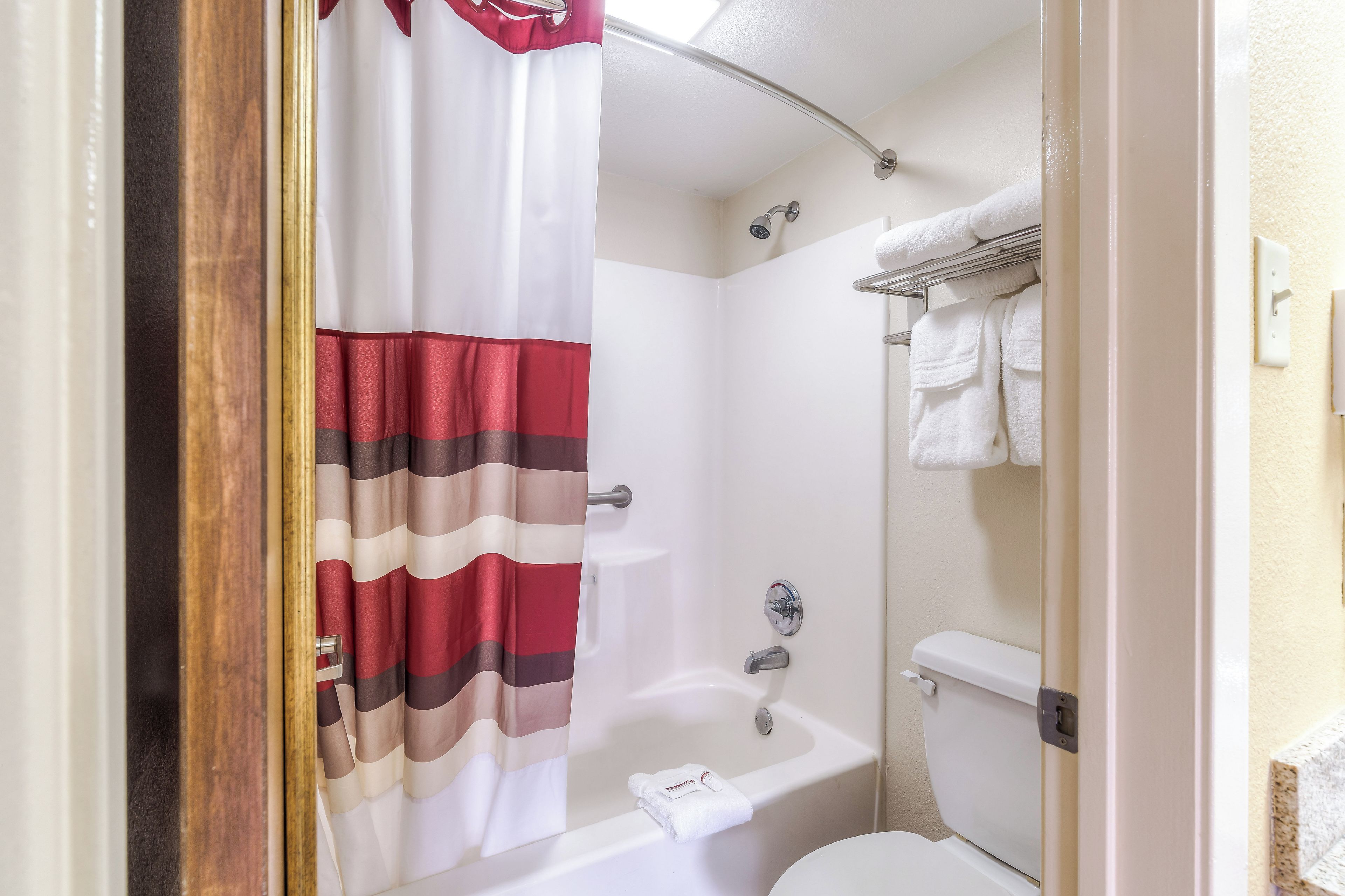 A bathroom with a shower curtain, a bathtub, a toilet, and a towel rack.