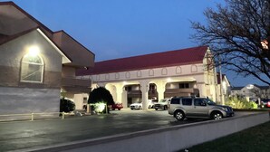 A building with a red roof, multiple arches, and parked cars. - Red Roof Inn Amarillo West (Amarillo)
