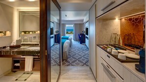 A modern hotel room with a large bed, a bathroom with a marble sink, and a view of the sea.