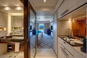 A modern hotel room with a large bed, a bathroom with a marble sink, and a view of the sea.
