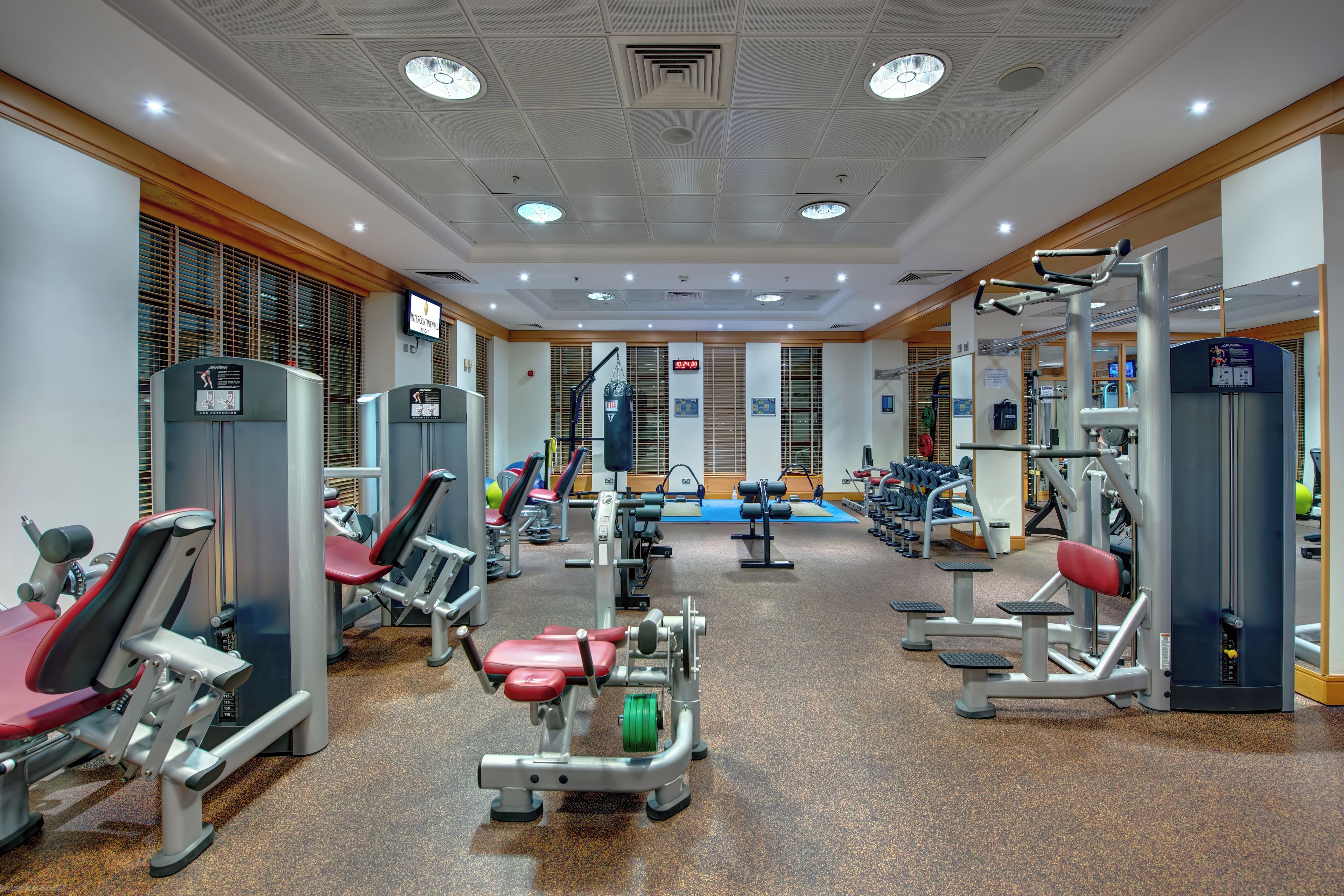 Ein Fitnessstudio mit verschiedenen Trainingsgeräten, darunter Kraftmaschinen und Kurzhanteln.