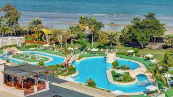 A resort with a large pool, a water slide, and a beach view.