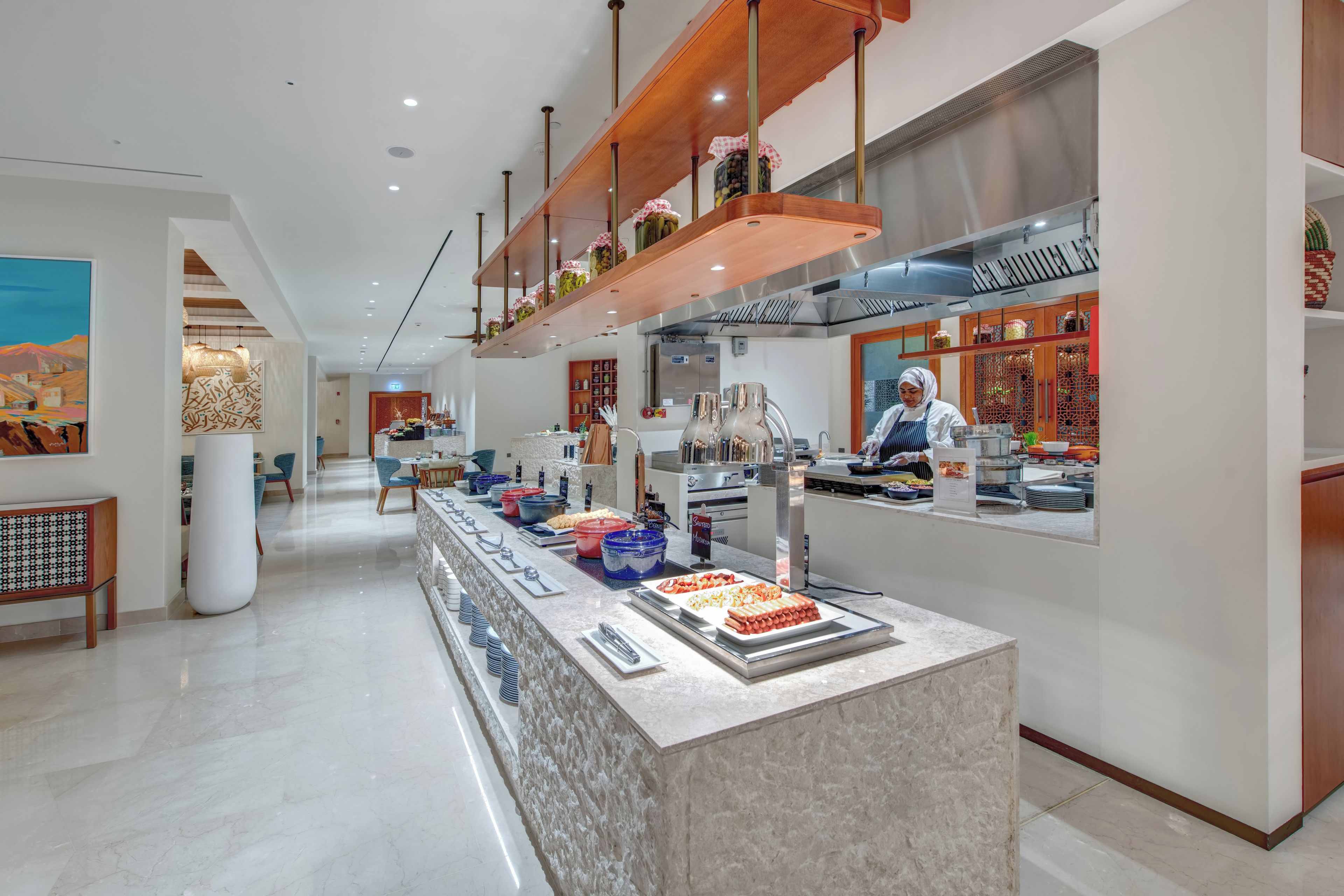 A modern kitchen area with a buffet setup, including a variety of food items and a person preparing food.