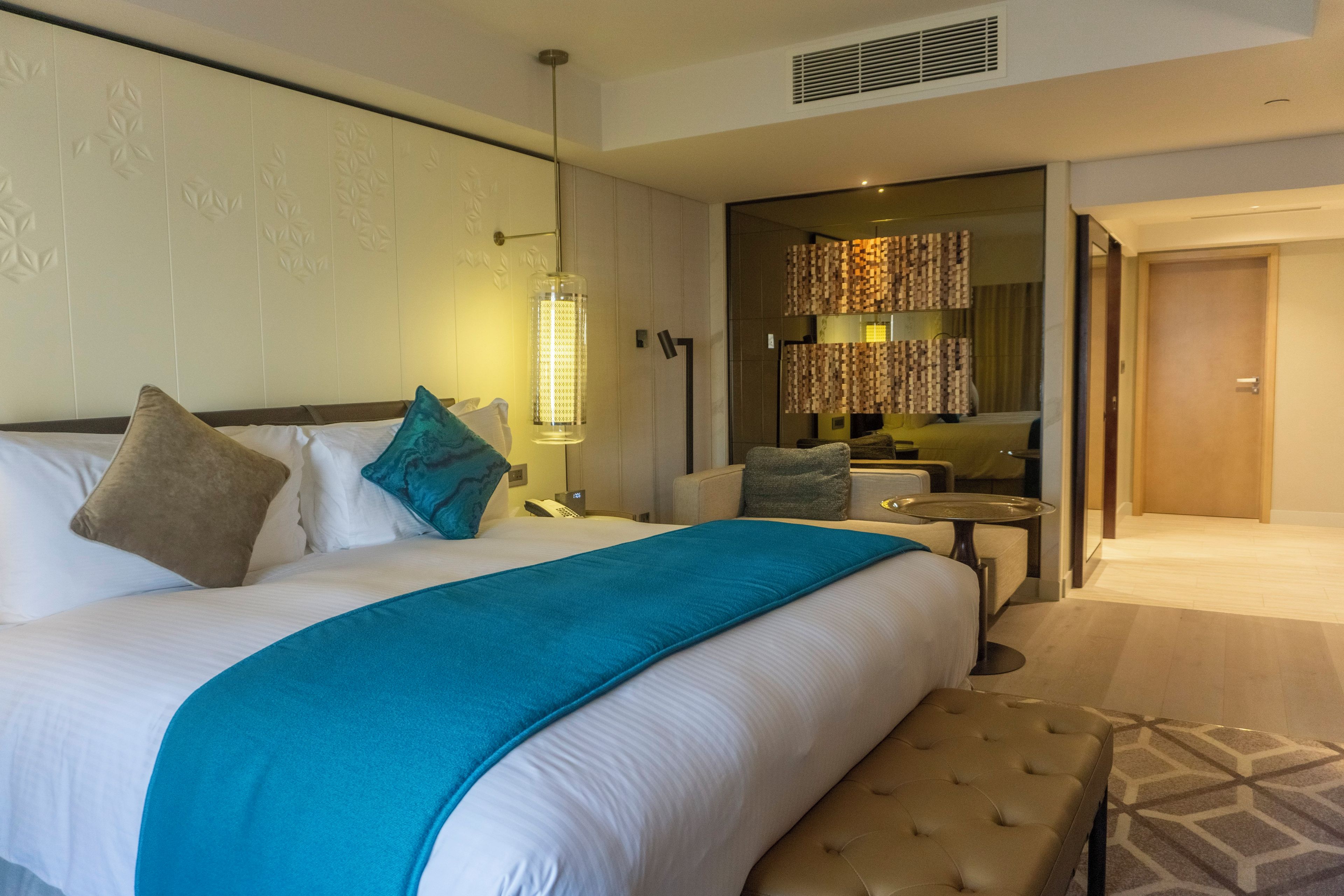 Une chambre d’hôtel avec un grand lit, une table de chevet, une chaise, une petite table et un miroir.