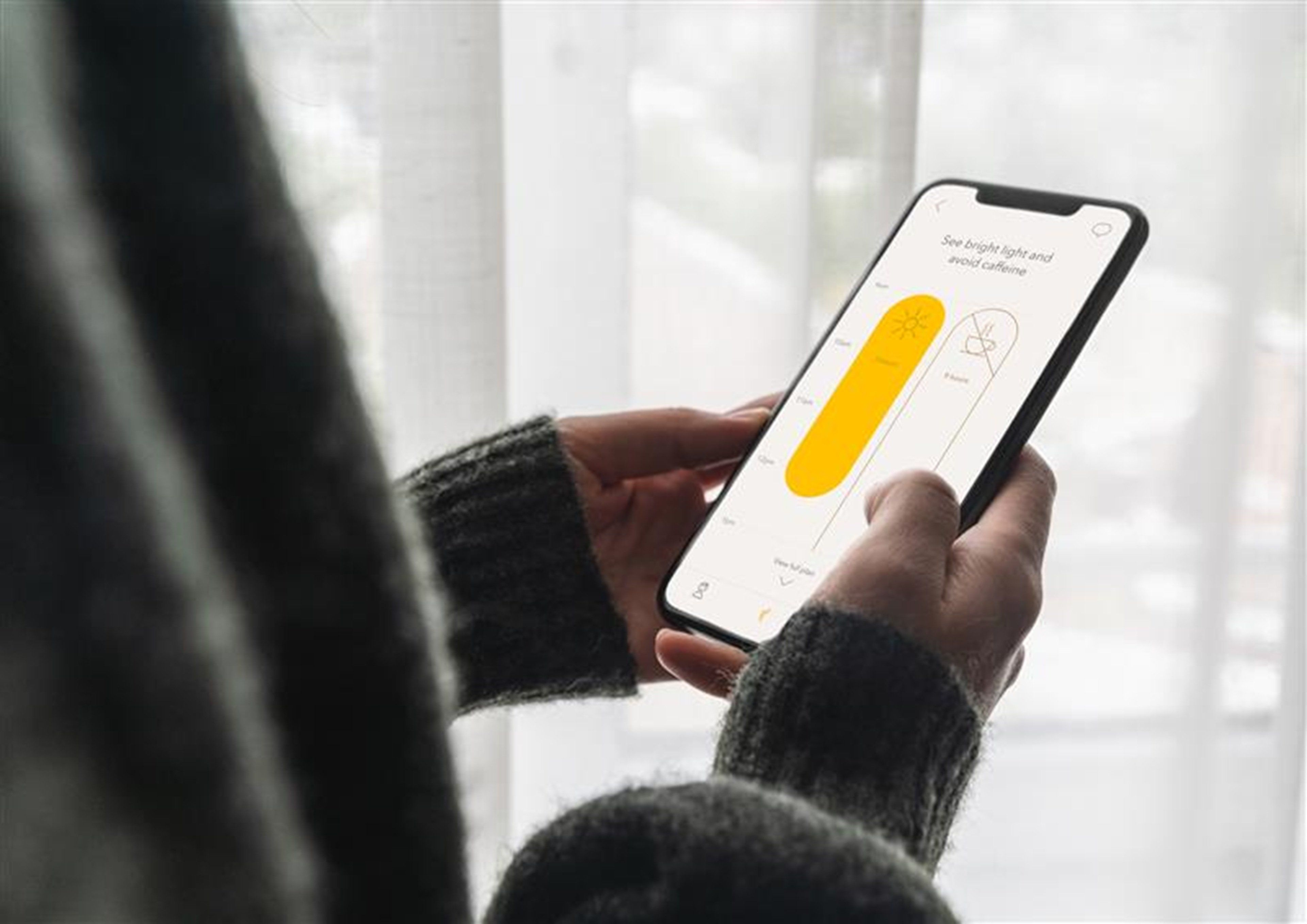 A person holding a smartphone with a health-related app interface.