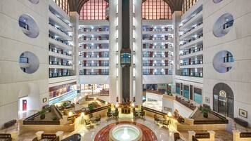 A multi-level hotel lobby with a central atrium, multiple floors with balconies, and a fountain in the middle.