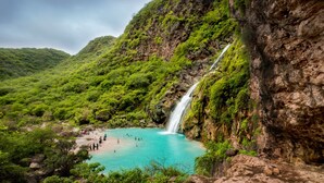 A natural landscape with a waterfall, turquoise pool, and lush greenery. - InterContinental Muscat by IHG (Muscat)