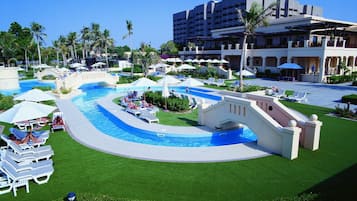 A resort with a swimming pool, lounge chairs, and palm trees.
