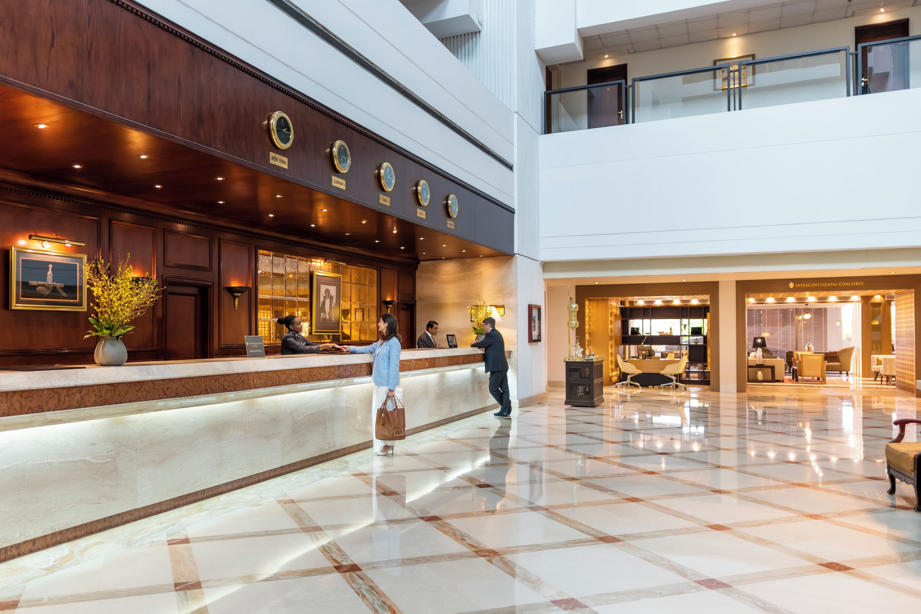 A hotel lobby with a reception desk, a seating area, and a dining space.