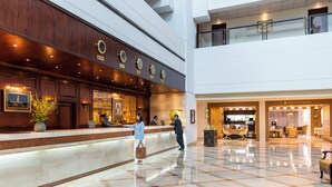 A hotel lobby with a reception desk, a seating area, and a dining space.
