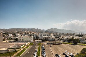 A cityscape with a large parking lot, modern buildings, and mountains in the background.