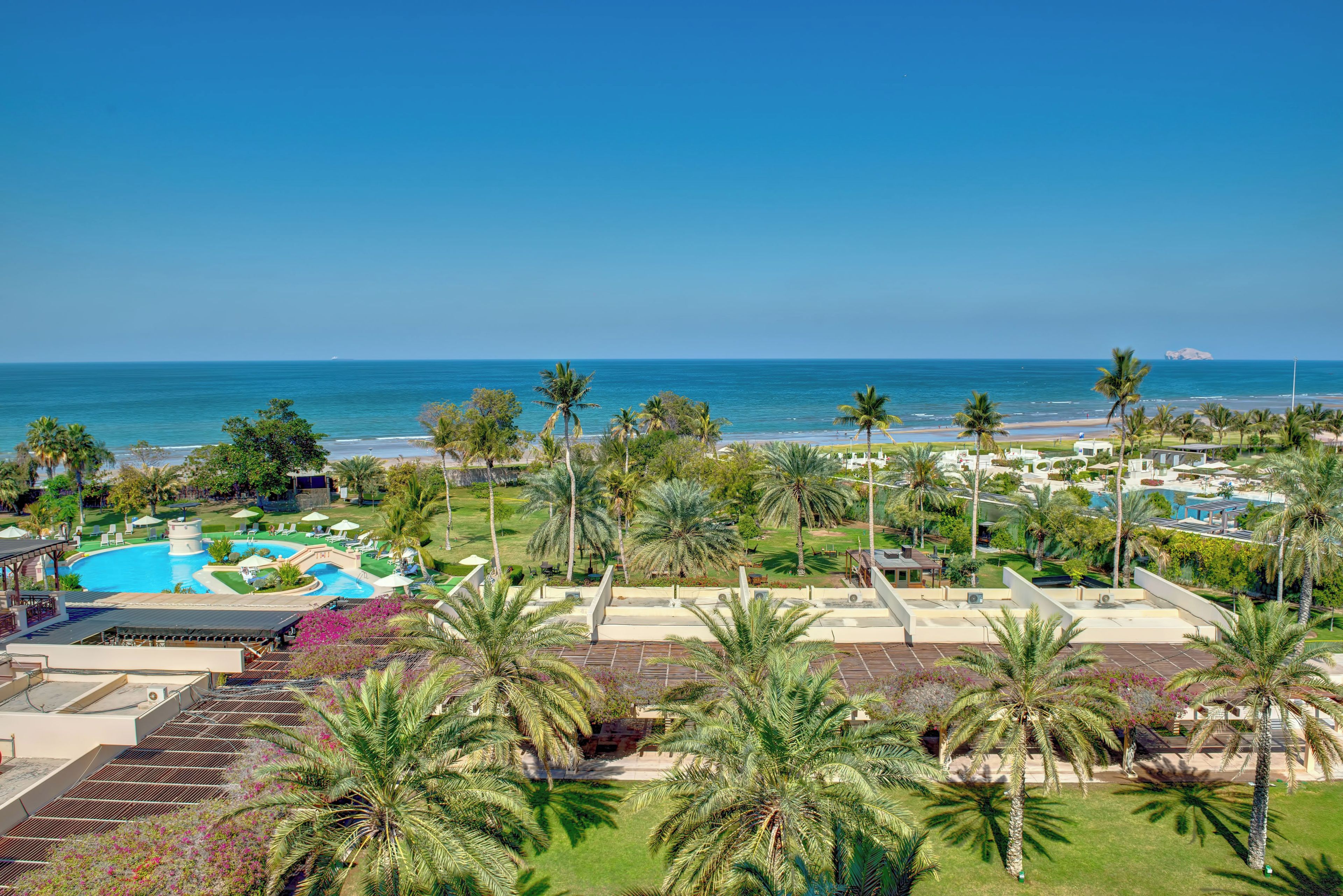Un resort con piscina, palmeras y vista al océano.
