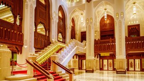 A grand lobby with a marble staircase, ornate wood paneling, and a chandelier. - InterContinental Muscat by IHG (Muscat)