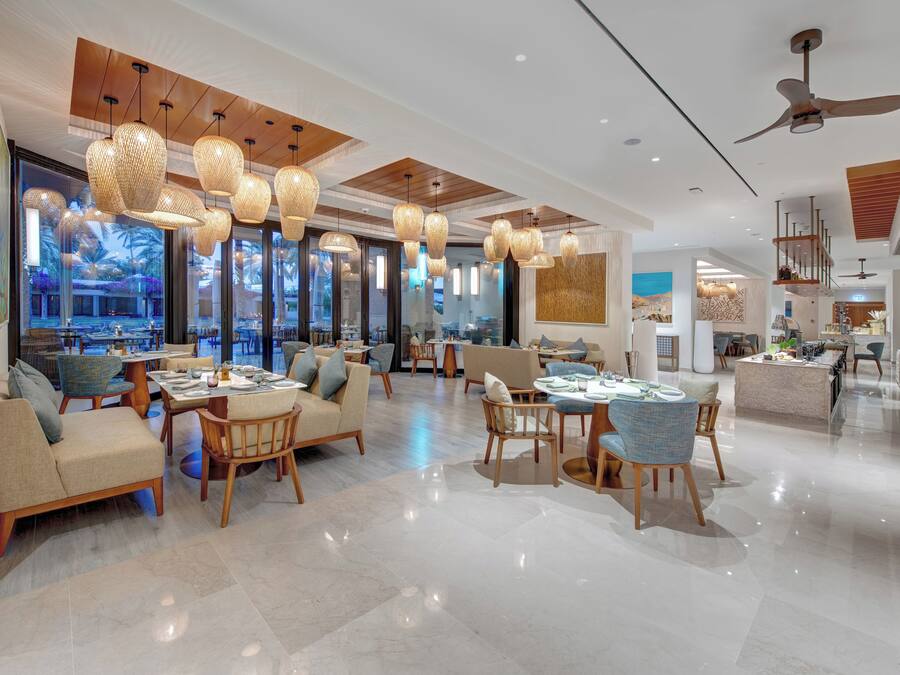 Un vestíbulo de hotel moderno con zona de comedor, ventanas amplias y ventilador de techo.