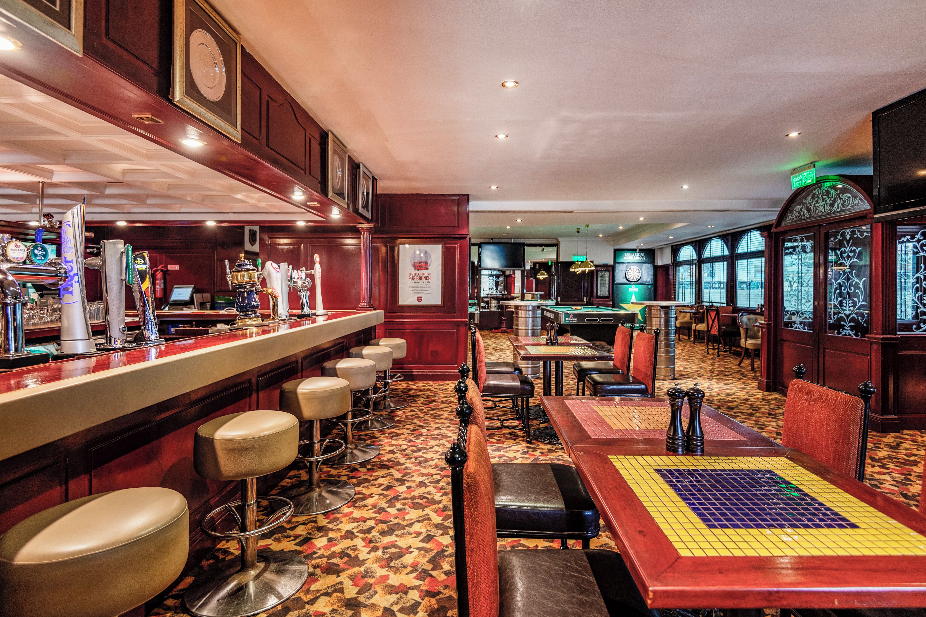 Zona de bar con taburetes, mesa de billar y mesa de futbolín.