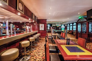 Zona de bar con taburetes, mesa de billar y mesa de futbolín.