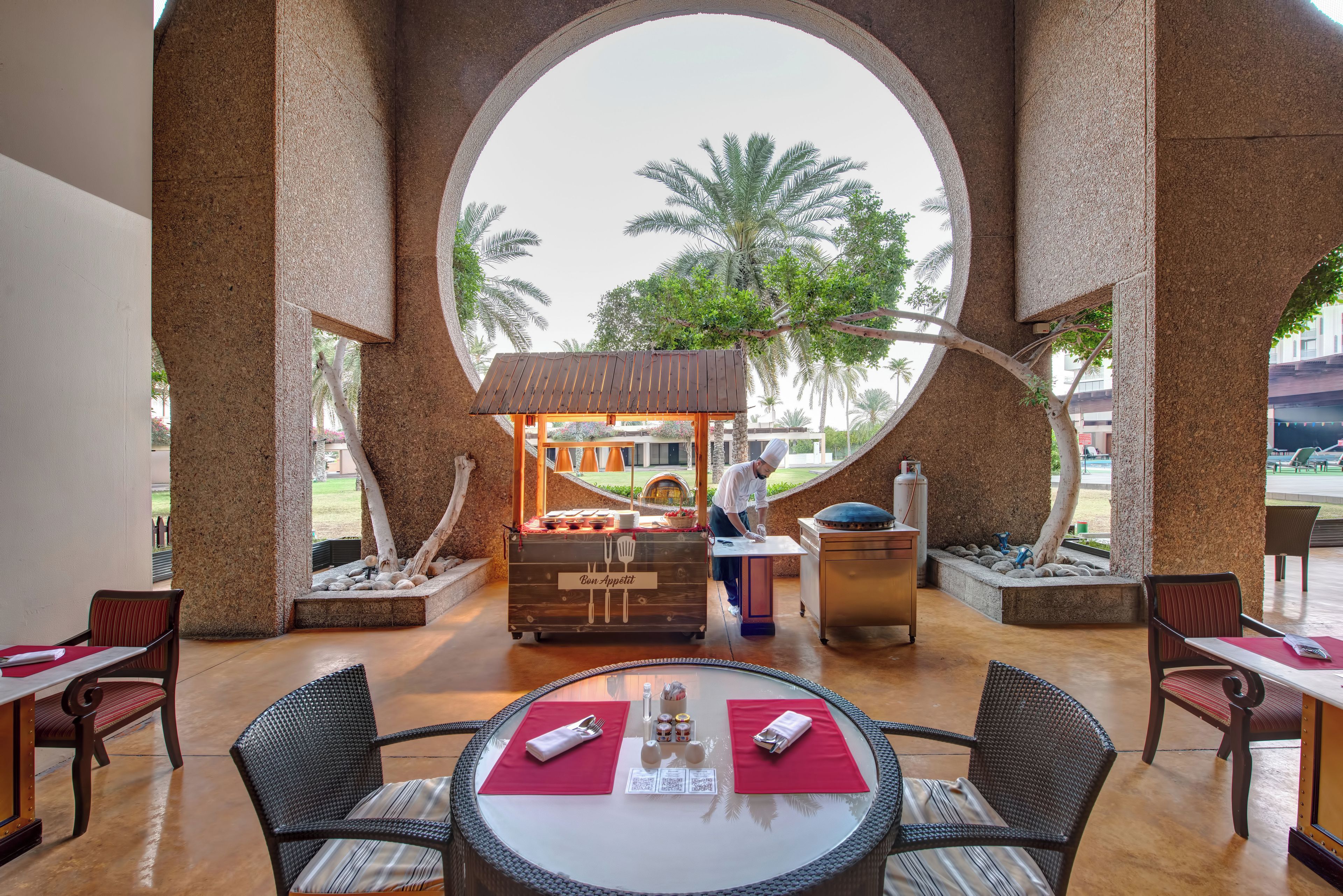 Een restaurant met uitzicht door een groot rond raam, met terras en een buffet.