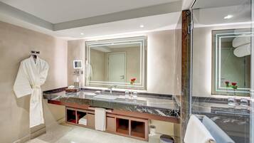 Une salle de bain moderne avec un grand miroir, un comptoir en marbre et un peignoir accroché au mur.