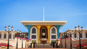 Un edificio grande con un arco central, flanqueado por alas simétricas y un asta de banderas en la parte superior.