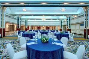 A banquet hall with round tables, white chairs, and blue tablecloths. - InterContinental Muscat by IHG (Muscat)
