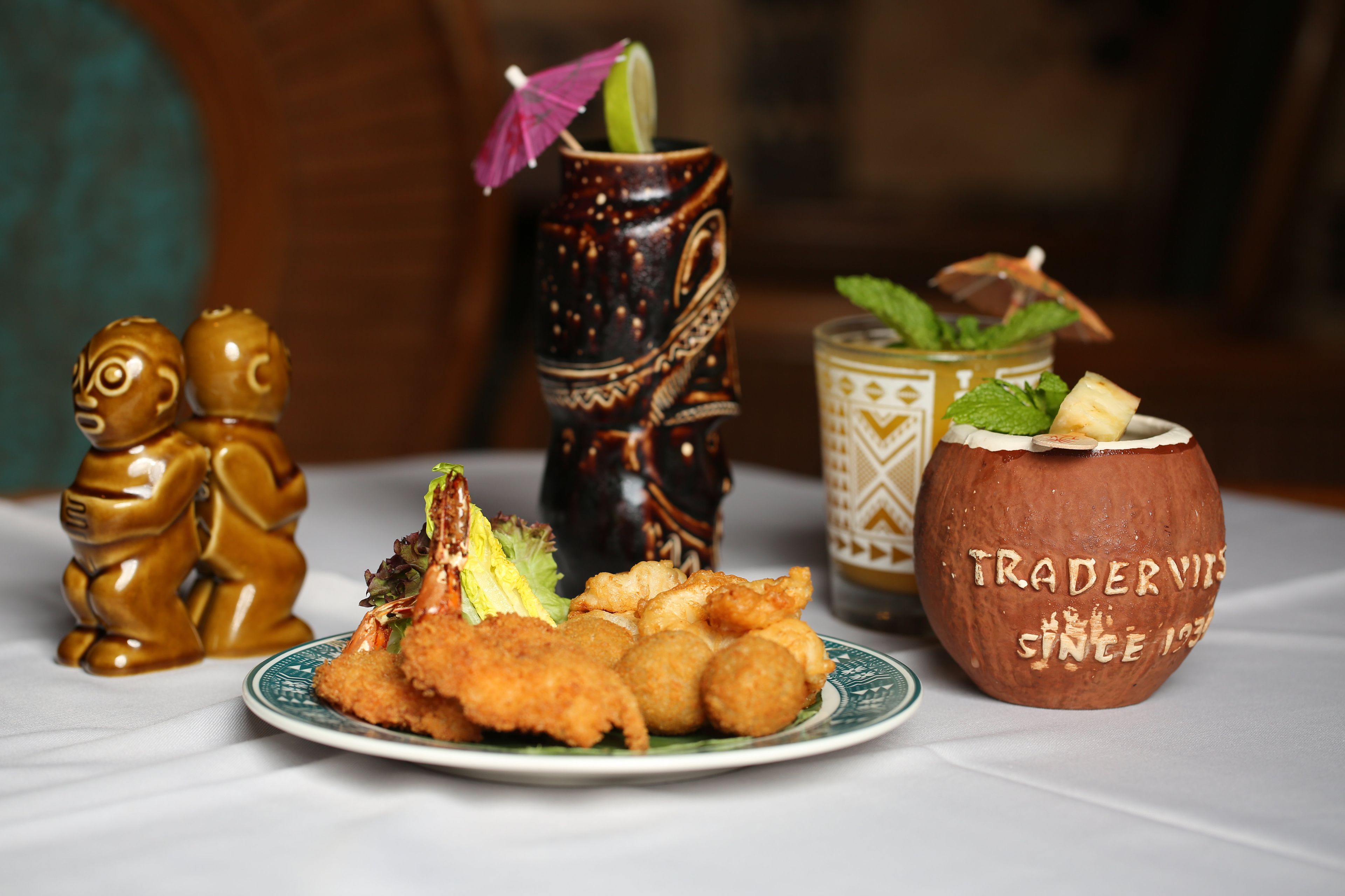 A plate of fried food, a decorative vase, and a coconut drink on a table.