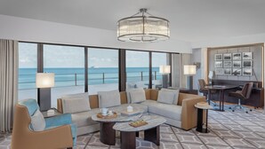 A modern hotel room with a large balcony, a chandelier, a sofa set, a coffee table, and a desk with a chair. - InterContinental Muscat by IHG (Muscat)
