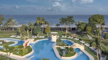 A resort with a large pool, sun loungers, and a view of the ocean.