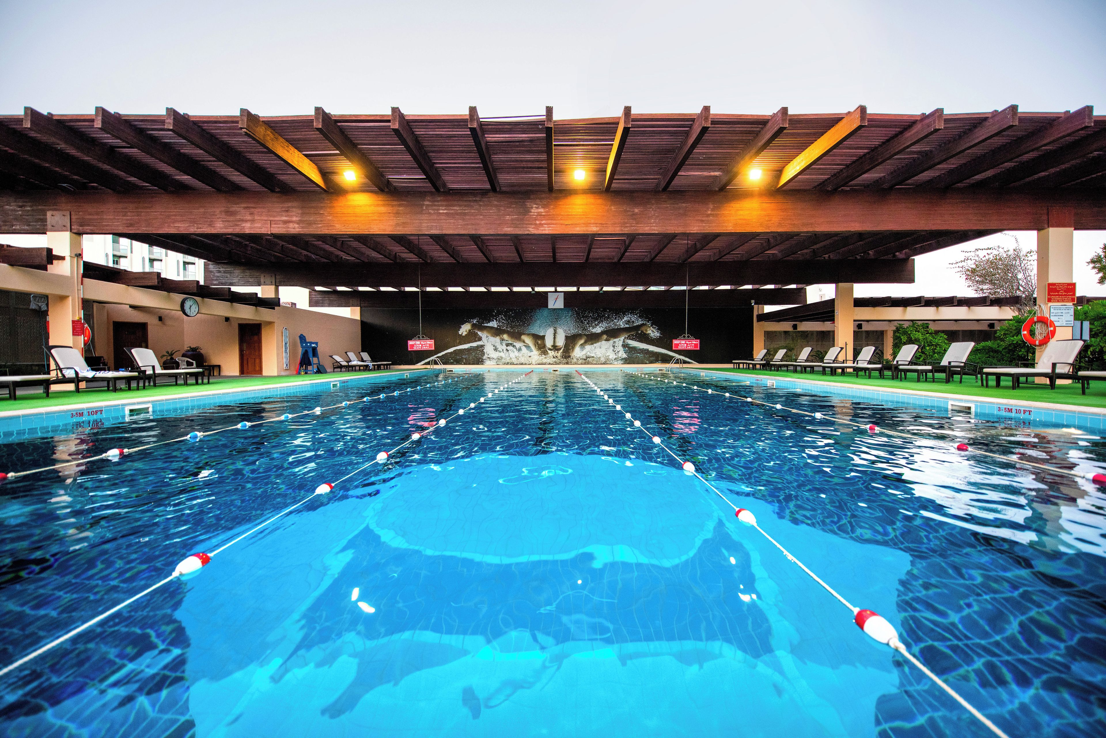 A swimming pool with a diving board and lounge chairs.