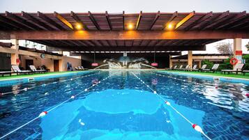 A swimming pool with a diving board and lounge chairs.