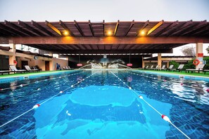 Una piscina con tabla de clavados y sillas de descanso.