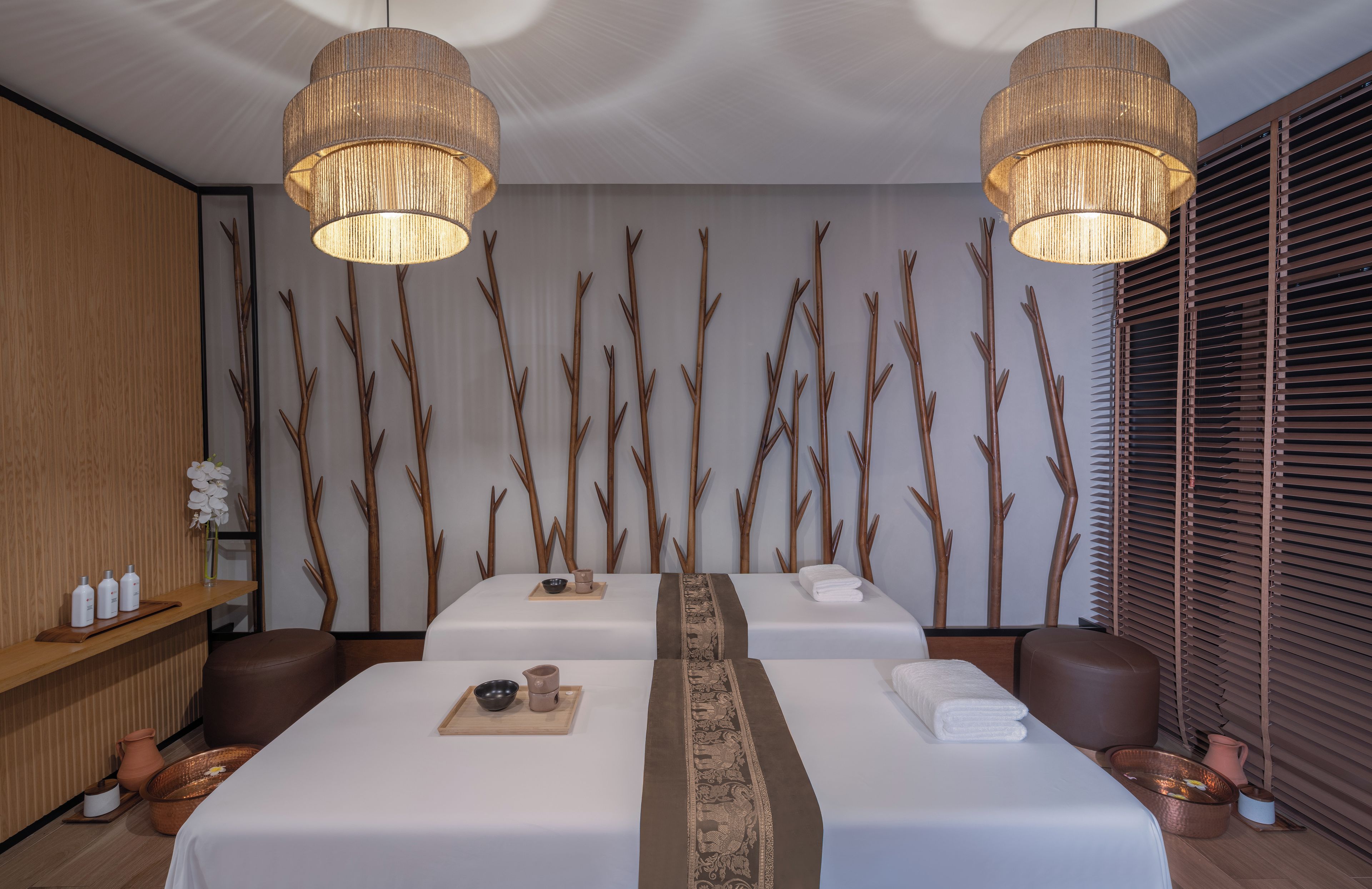 Un cuarto de spa con dos camas, decoración de madera y un ventanal con persianas.