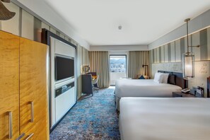 A hotel room with two beds, a desk, a TV, and a large wardrobe.