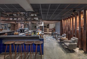 Una cocina moderna con barra, taburetes y una zona de estar con una silla.