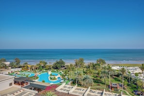 Un resort con piscina, playa y palmeras.