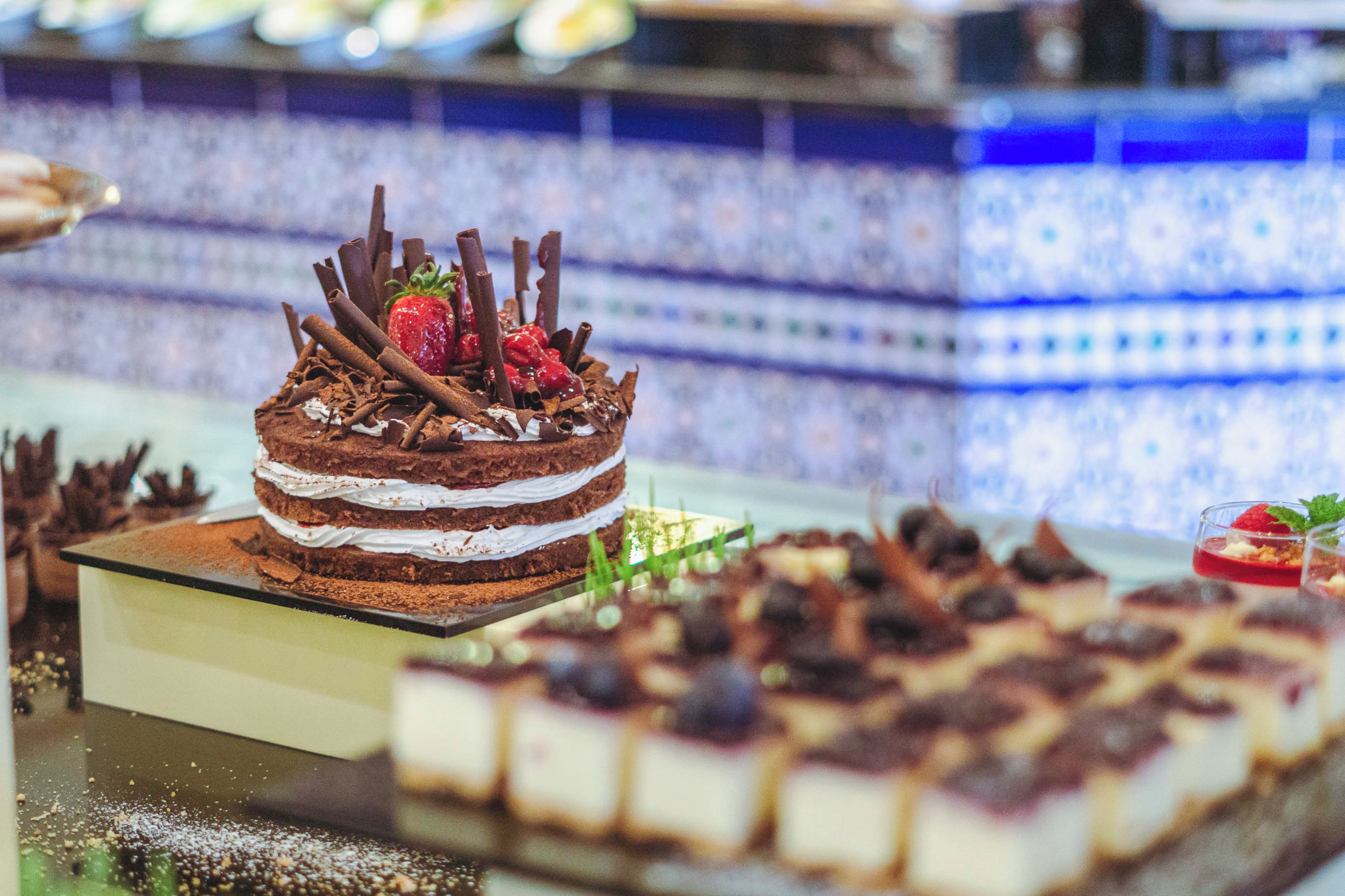 Ein mehrschichtiger Schokoladenkuchen mit Erdbeeren und Schokoladostreuseln auf einer Glaskonsole.