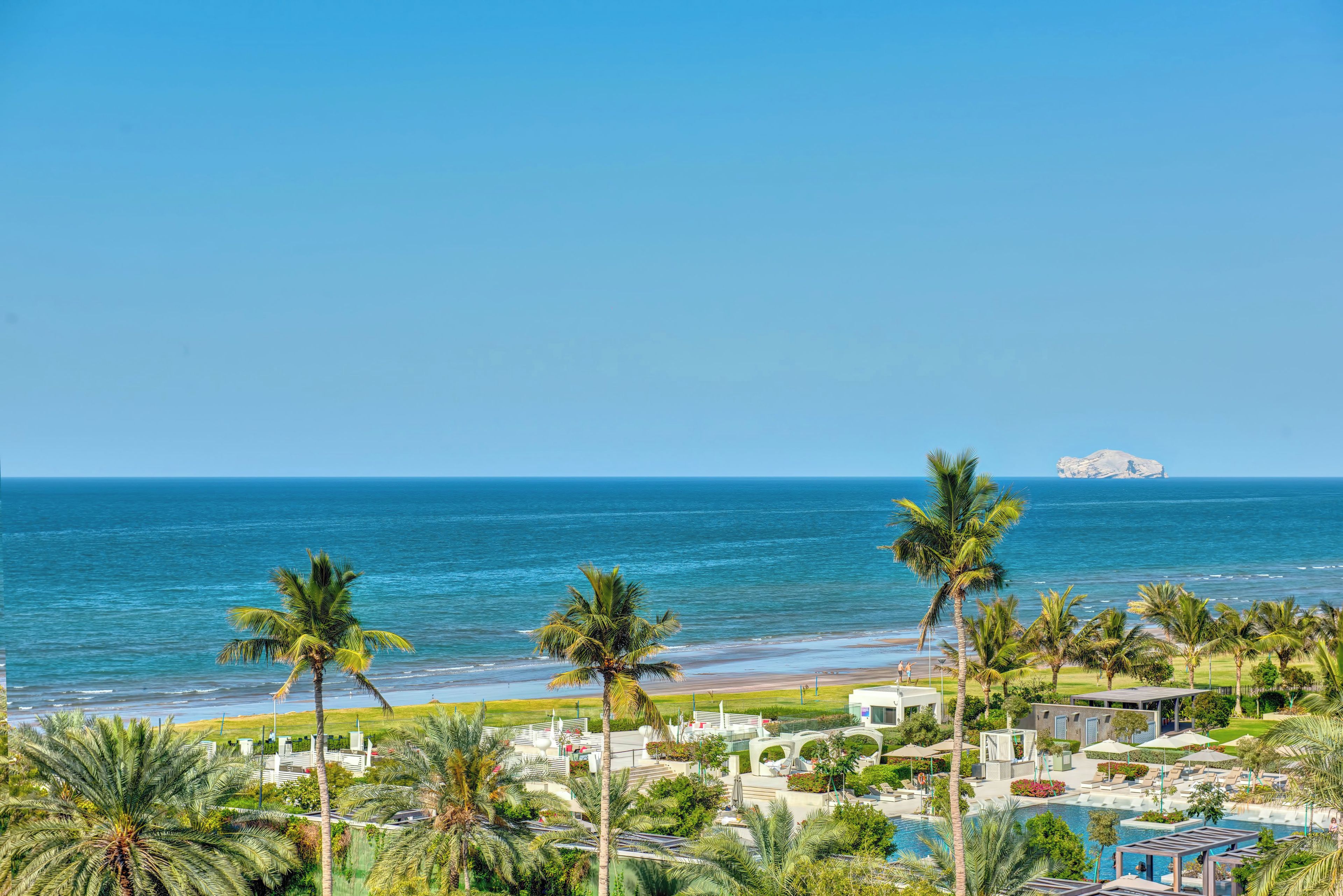 Un resort con piscina, palmeras y vista al océano.