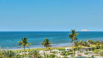 Un resort con piscina, palmeras y vista al océano.