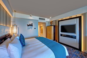 Habitación de hotel moderna con una cama grande, un televisor de pantalla plana, un armario y un adorno en la pared.